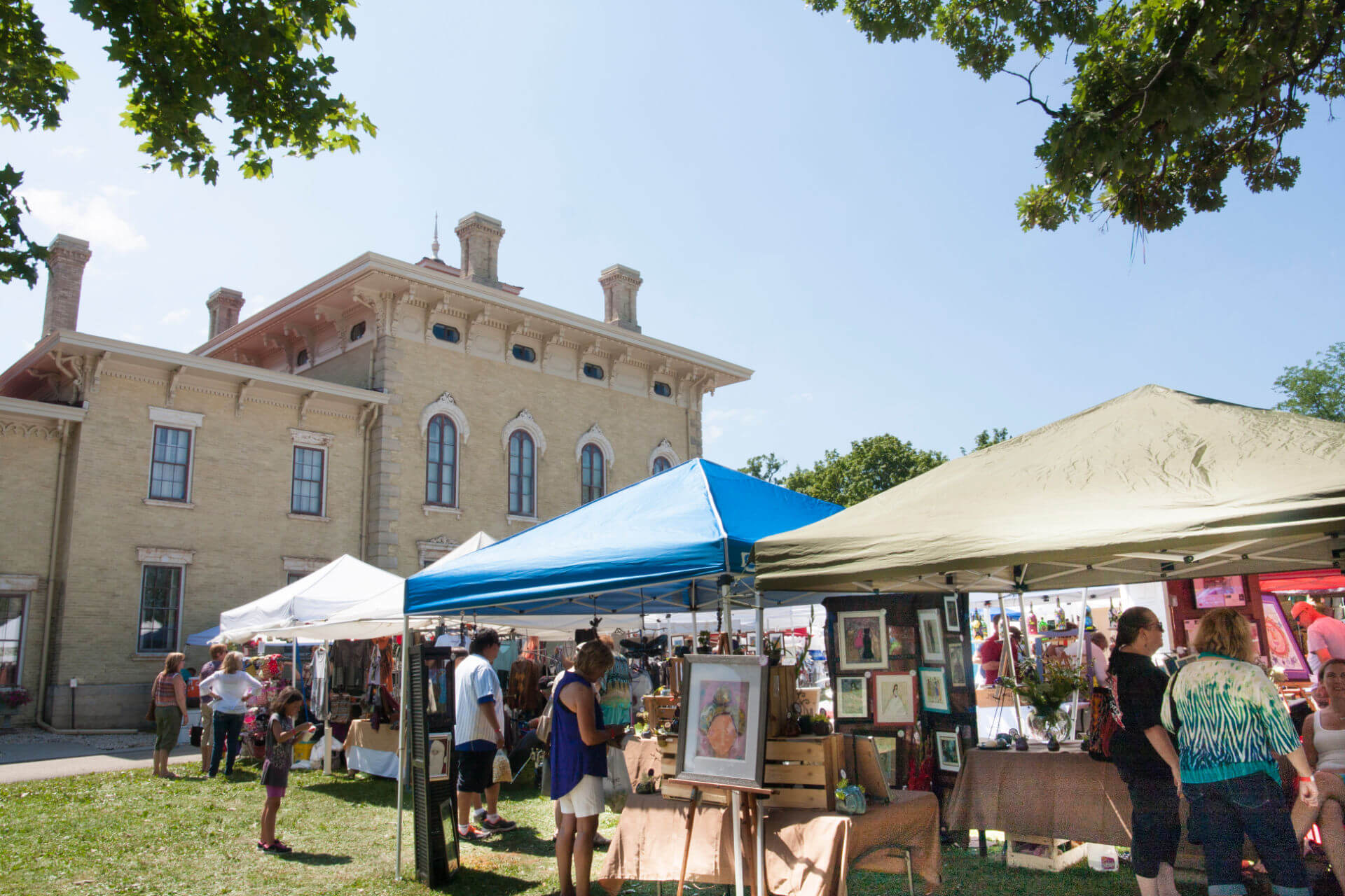 Patrons of the Tallman Arts Festival browse artists' works underneath tents, with the Lincoln-Tallman House in the background